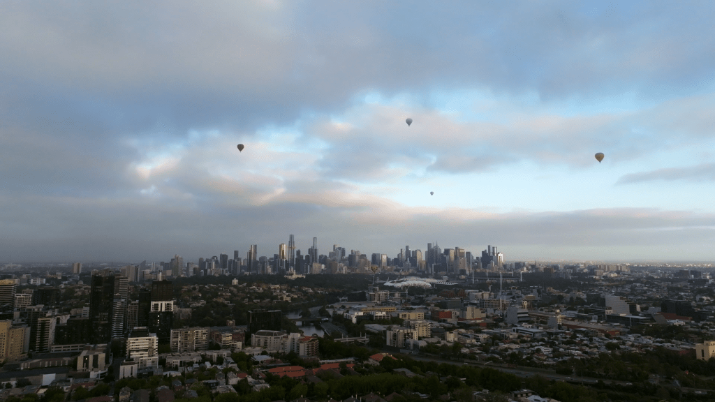 Melbourne Skyline view from a drone with hot air balloons floating through the clouds